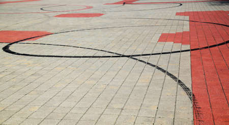 Traces of burnt tires motorcycle on the pavement of gray and red stones