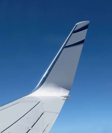 The wingtip of an airliner in flight against a dark blue skyの写真素材