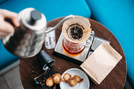 Hand drip coffee, barista pouring water on coffee ground with filter. Simple set for manual brewing.の写真素材