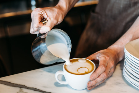 Barista pouring latte foam over coffee, espresso and creating a perfect latte art.の写真素材