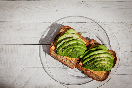 Avocado sandwich with herbs, cheese and toasted bread on the wooden white background. Top view, place for textの写真素材