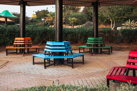 Park colored benches located around the column. Blue, orange, green and redの写真素材