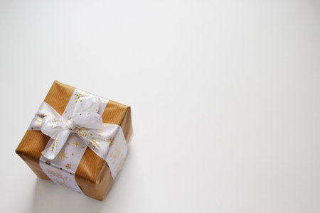 Gift box on white background. Vintage closeup. Christmas gift in craft paper with gold ribbon.の写真素材
