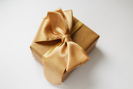 Christmas gift in craft paper isolated at white background. Gift box with gold ribbon.の写真素材