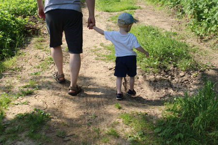 Happy family leisure. Man holds little boy by the hand while walking.の写真素材