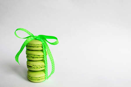 Green macaroon cakes with a light green ribbon on a white background.の写真素材