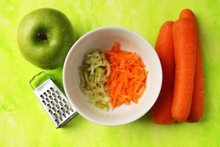 Grated apple and carrot in a small white plate.の写真素材