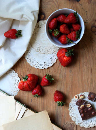 Strawberries and chocolate on an old wooden table. Vintage style. Design wallpaper for your desktop or calendar.の写真素材