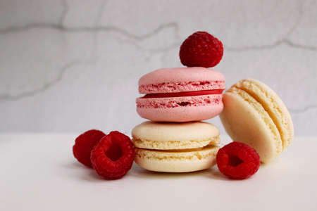 Pink and white macaroon cakes with raspberries on the table.の写真素材