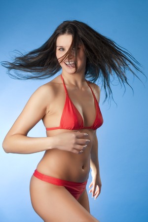 Image of a bright brunette in a red bathing suit on a blue backgroundの写真素材