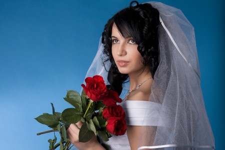 Image of the brunette bride with red roses on a blue backgroundの写真素材