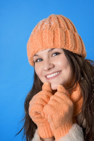 Picture of a beautiful brunette girl in the orange cap and coat on a blue backgroundの写真素材