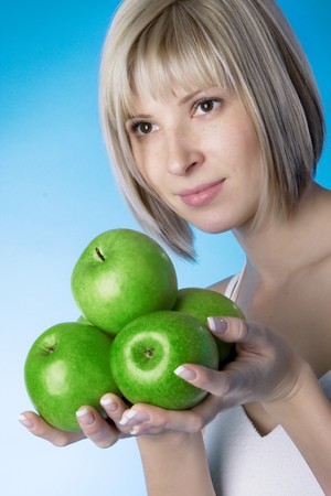 Image of a smiling girl with a green apple on a blue background.の写真素材