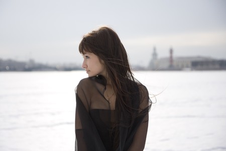 Picture of a girl in a black dress against a background of snow and the cityの写真素材