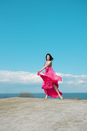 Image of a girl in bright pink dress against the backdrop of blue sky.の写真素材