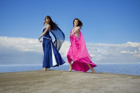 Images of girls dancing on the sky in bright dressesの写真素材