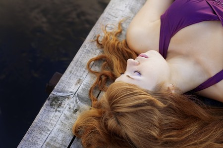 Images of a beautiful red-haired girl on the pier in a purple dressの写真素材