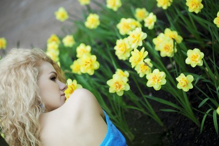 The image of a beautiful positive girl in a park, surrounded by flowersの写真素材