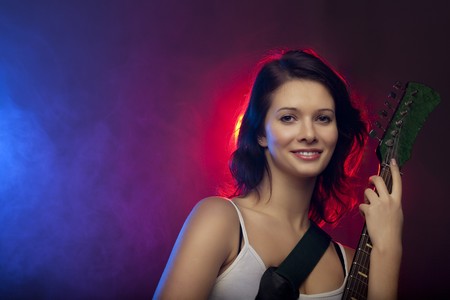 Image of a beautiful girl with a guitar in the spotlightの写真素材