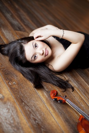 The image of a beautiful asian girl with a violin on the parquet floorの写真素材
