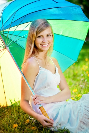 Beautiful smiling woman with a rainbow umbrella outdoors の写真素材