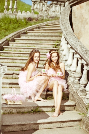 Beautiful twins whith cups of tea or coffeeの写真素材