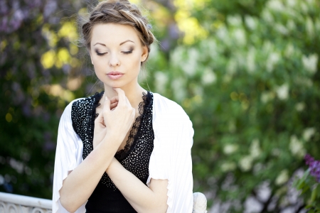 Beautiful woman with a hair braid and stylish make up on the background of a blossoming park.の写真素材