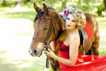 Woman in red dress with bright makeup on the horse outdoorsの写真素材