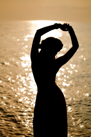 Luxurious beautiful fashionable woman on the beach at sunsetの写真素材