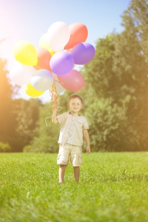 Child with a bunch of balloons in their handsの写真素材