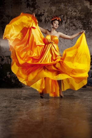 Young lady in flying silk dress on grunge backgroundの写真素材