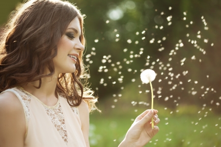 Beautiful young woman blowing a dandelion
の写真素材