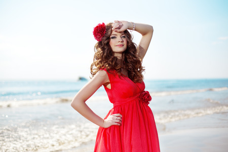 Beautiful woman in a bright red dress by the seaの写真素材