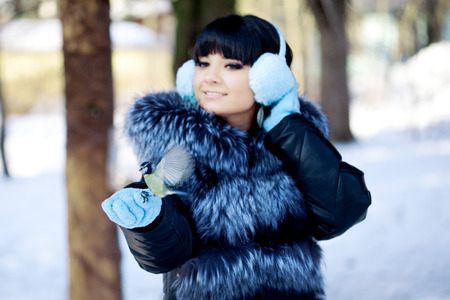 Young woman feeding birds in the winter forest