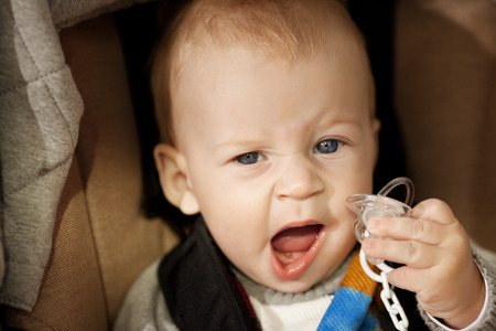 Cute little smiling baby in a baby carriage on the streets of the city. Smile of a child sitting in...