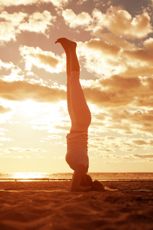 Young beautiful slim woman silhouette practices yoga on the beach at sunrise. Yoga at 
sunsetの写真素材