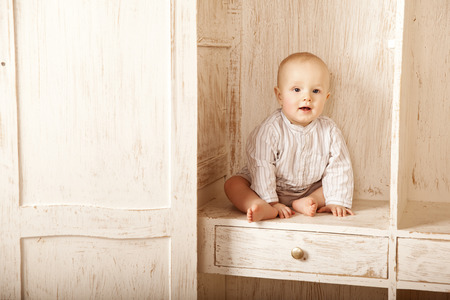 Beauty little baby sitting in the closet. Smiling child and interior of a bedroom. Cute kidの写真素材