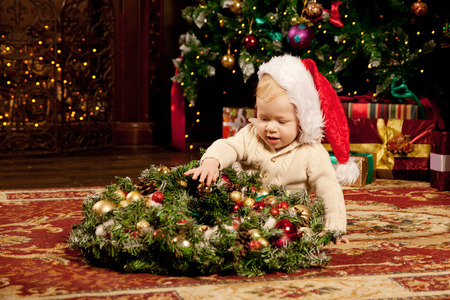Nice baby near the Christmas tree. Little boy celebrating Christmas. Cute smiling child with New Year gifts. Christmas Toddler の写真素材
