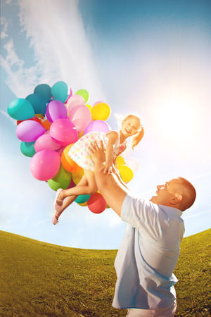 Father throws daughter. Familly playing together in park with balloons. Father tosses a baby against the skyの写真素材