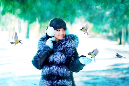 Winter woman on winter background. Woman Young girl feeding birds in the winter landscape.  Winter scene.の写真素材
