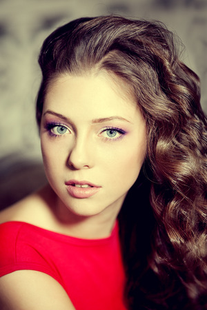 Slim trendy, luxurious, fashion woman in  lux vintage interior with long beauty hairstyle. Girl in red short dress on a luxury backgroundの写真素材