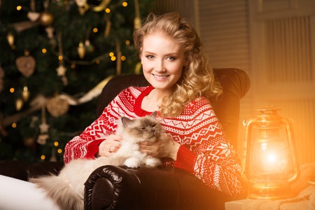 Christmas party, winter holidays woman with cat. New year girl. christmas tree in interior background.の写真素材