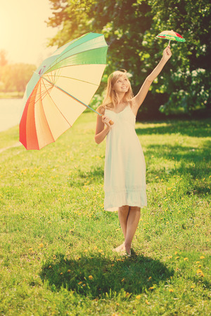 Beautiful smiling woman with two rainbow umbrellas, outdoorsの写真素材