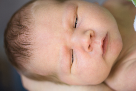 Newborn baby in the arms of mom, dad. Big hands of mother, father and small childの写真素材