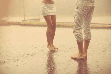 Loving couple in the rain barefoot. A man and a woman in love.の写真素材