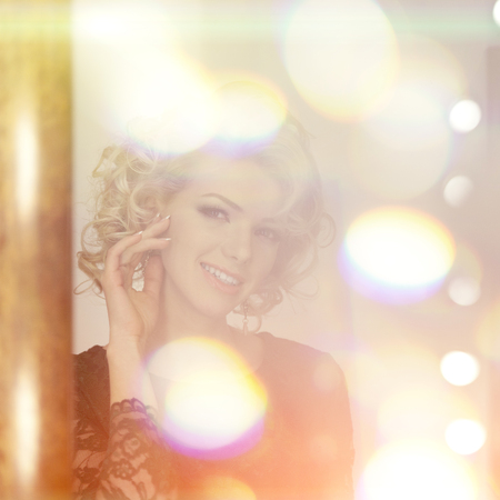 Beauty young model woman in luxurious evening dress in a fairy luxury apartment. Beautiful makeup and hairstyle. Classic vintage home interior. Light rays of a nightclub.の写真素材