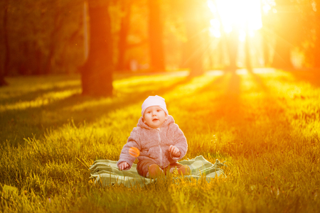 Baby in the park in the rays of sunset. Toddler on the nature outdoors. Backlight. Summertime family  sceneの写真素材