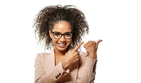 Positive Woman surprise showing product. Attractive young female with Afro hairstyle presenting product. Girl points aside with cheerful expression.  African American Model shows something amazing at blank spaceの写真素材