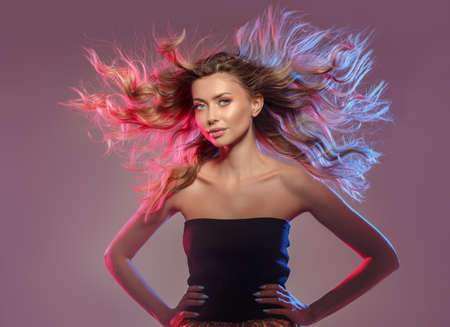 Girl with flying hair in blue and pink light. A woman in a nightclub dancing at a disco. Model with...