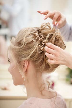 Makeup artist, hair professional stylist makes young beautiful bride bridal makeup before wedding in a morningの写真素材